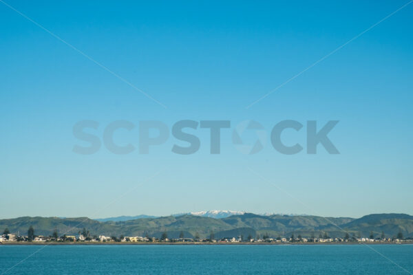 A blue sky winter morning at Perfume Point looking towards westshore and the snow capped Kaweka Ranges, Ahuriri, Napier, Hawke’s Bay, New Zealand - SCP Stock