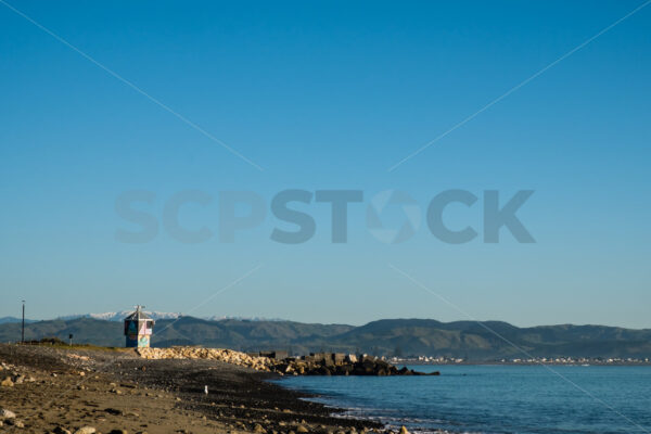 A blue sky winter morning looking towards Perfume Point lighthouse and thesnow capped Kaweka Ranges at the Perfume Point Reserve beach, Ahuriri, Napier, Hawke’s Bay, New Zealand - SCP Stock