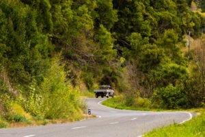 A farm ute and a Huntaway dog on the back driving down a twisty road, Hawke’s Bay, New Zealand - SCP Stock