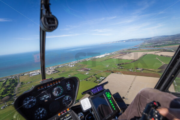 Aerial view looking towards Cape Kidnappers and the ocean from the passenger seat of a Helicopter, Hawke’s Bay, New Zealand - SCP Stock