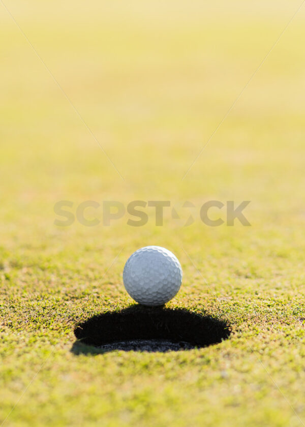 Hole in one.  A golfball teetering on the edge, Hawke’s Bay, New Zealand - SCP Stock