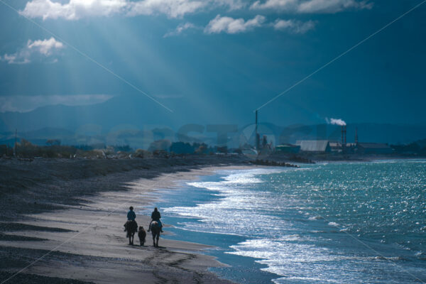 Riding along the beach under a stormy sky, Clive, Hastings, Hawke’s Bay, New Zealand - SCP Stock