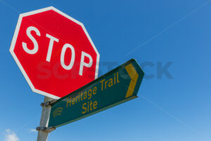 Road intersection stop and Heritage Trail Site sign against a blue sky - SCP Stock