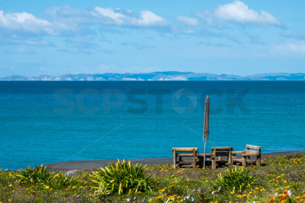 Wooden chairs and parasol on the beachm, Napier, Hawke’s Bay, New Zealand - SCP Stock