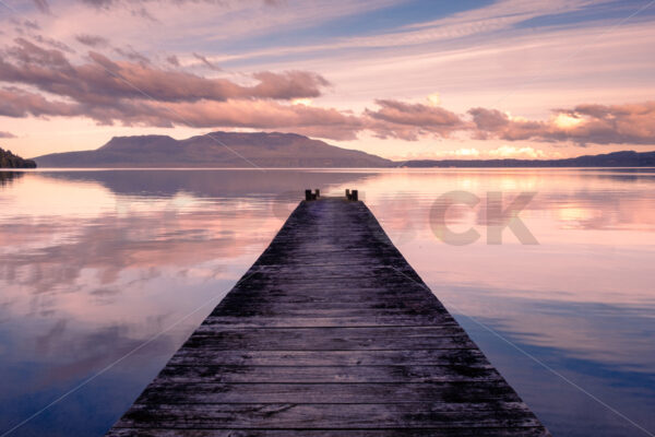 A Lake Tarawera jetty at sunset with Mount Tarawera in the distance, Rotorua, Bay of Plenty, New Zealand - SCP Stock