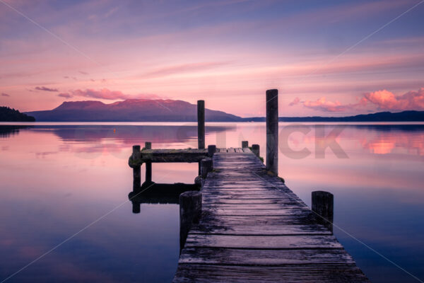 A Lake Tarawera jetty at sunset with Mount Tarawera in the distance, Rotorua, Bay of Plenty, New Zealand - SCP Stock