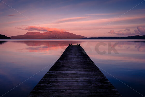 A Lake Tarawera jetty at sunset with Mount Tarawera in the distance, Rotorua, Bay of Plenty, New Zealand - SCP Stock