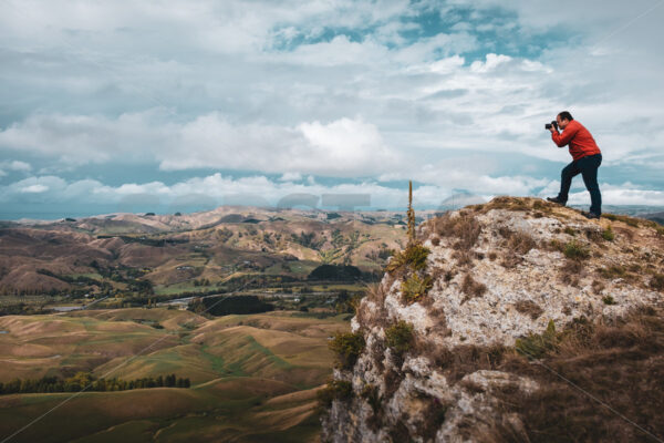 A Photographer stood at the top of Te Mata Peak photographing the Tukituki valley, Hawke’s Bay, New Zealand - SCP Stock